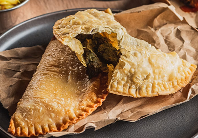 Empanada de Pino in Chile. Break the empanada open before shooting. Window light angled from the side highlights the contrast between the shiny baked crust and the colorful filling inside.