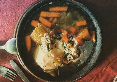 Take a top-down overhead photo before eating to capture the vibrant color contrast between the bright orange squash, yellow corn, green cilantro, and clear broth.