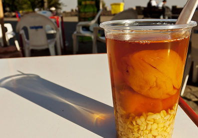 Hold the glass near a bright window or shaded outdoor table. Backlighting makes the amber syrup glow while keeping the wheat and peach easy to see.