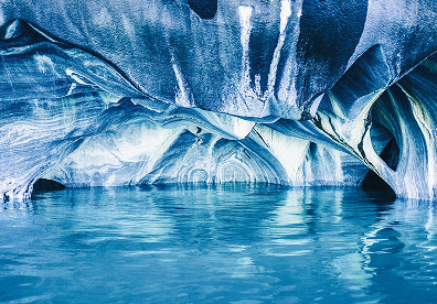 Hold your phone low toward the waterline while staying safely seated in the boat. You get the richest shot when you capture both the smooth marble ceiling and the bright blue water beneath it.